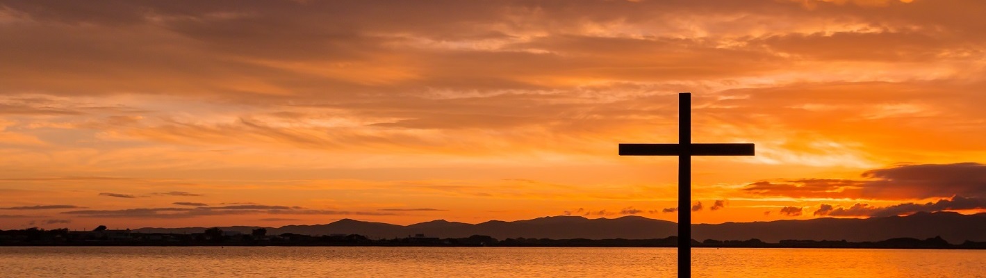 Christian cross in ocean at sunset